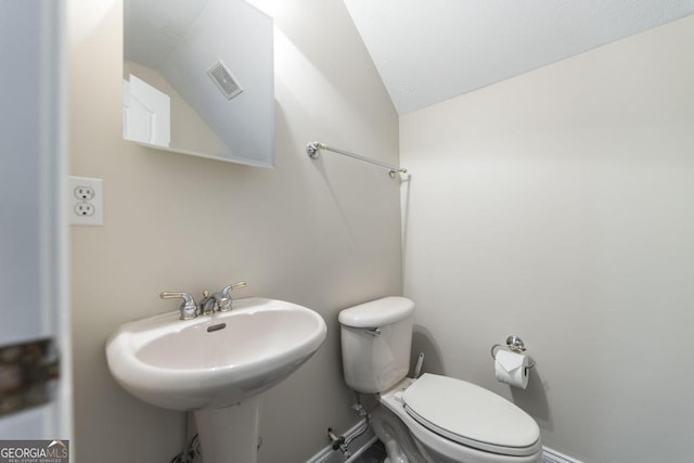 half bath featuring lofted ceiling, visible vents, a sink, and toilet