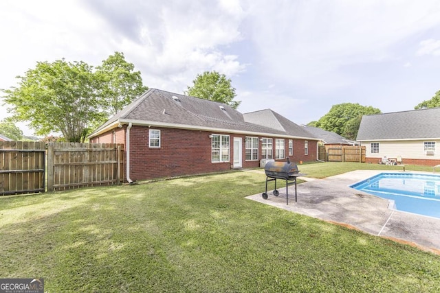 back of house with a patio area, a shingled roof, a fenced backyard, a yard, and brick siding