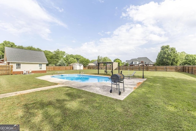 view of swimming pool featuring a storage unit, a lawn, an outbuilding, and a fenced backyard