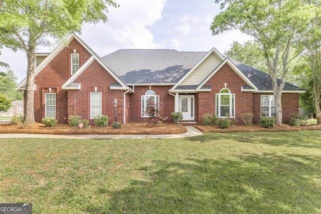 view of front of property featuring brick siding, a shingled roof, and a front yard