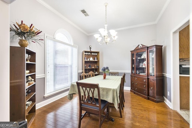 dining area with wood finished floors, a chandelier, baseboards, ornamental molding, and visible vents