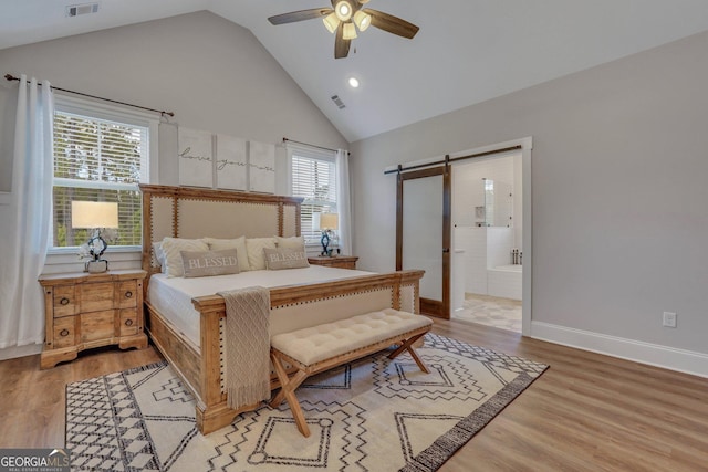 bedroom with light wood-style flooring, visible vents, high vaulted ceiling, and a barn door