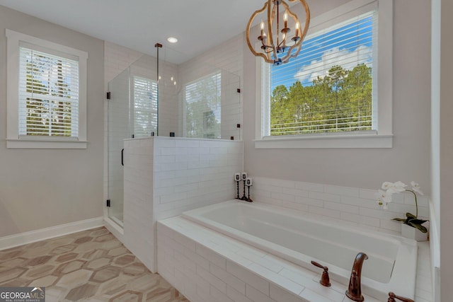 full bath with a bath, an inviting chandelier, a healthy amount of sunlight, and a stall shower