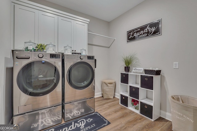 laundry area featuring baseboards, cabinet space, wood finished floors, and washer and clothes dryer