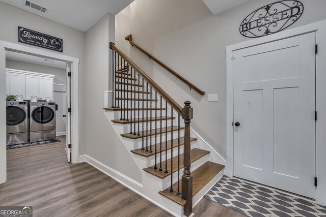stairway featuring washing machine and clothes dryer, wood finished floors, visible vents, and baseboards