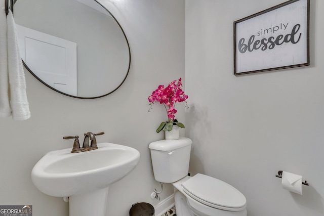 half bathroom featuring toilet, a sink, and baseboards