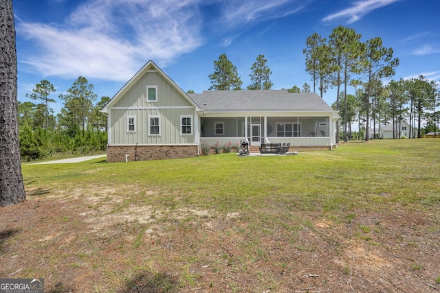 back of property with a lawn, a sunroom, board and batten siding, and a shingled roof