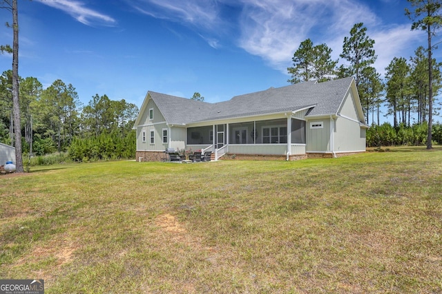 rear view of house featuring a yard, a sunroom, and a shingled roof