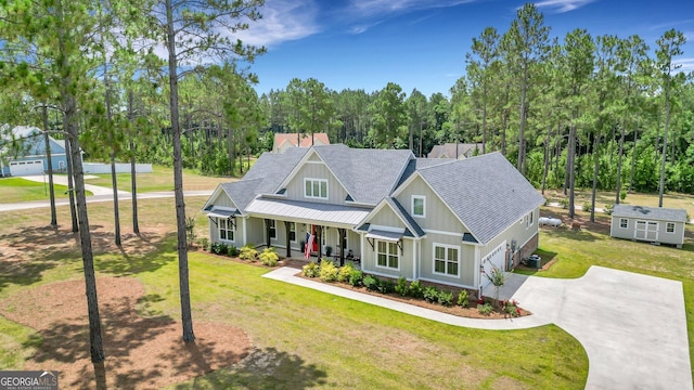 craftsman house with a front lawn, concrete driveway, board and batten siding, a porch, and roof with shingles