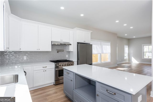 3286 Bachelor St, East Point, GA 30344 - kitchen with white cabinets, stainless steel appliances, light wood finished floors, tasteful backsplash, and under cabinet range hood