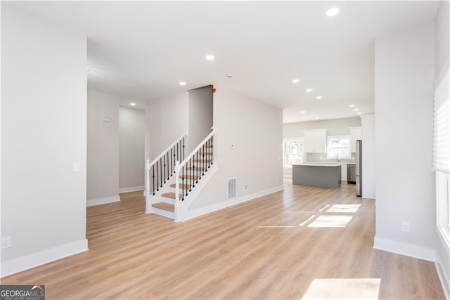 3286 Bachelor St, East Point, GA 30344 - unfurnished living room featuring light wood finished floors, baseboards, visible vents, and stairs