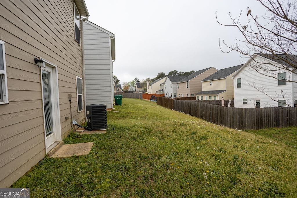 view of yard featuring central air condition unit, fence, and a residential view