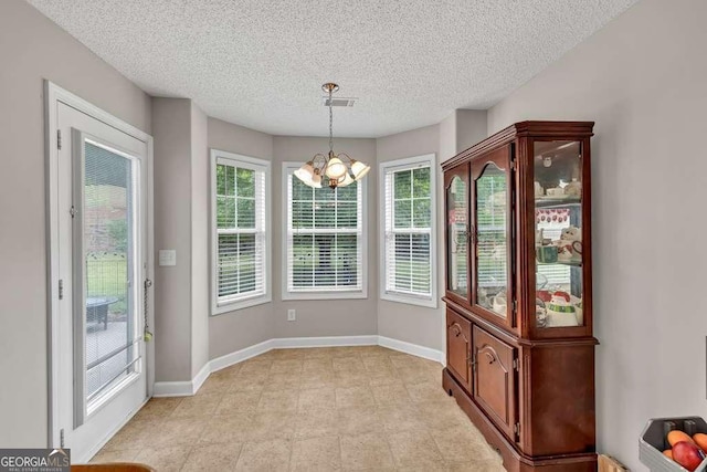 180 Laurel Oaks Ln, Jefferson, GA 30549 - unfurnished dining area with a chandelier, plenty of natural light, baseboards, and a textured ceiling
