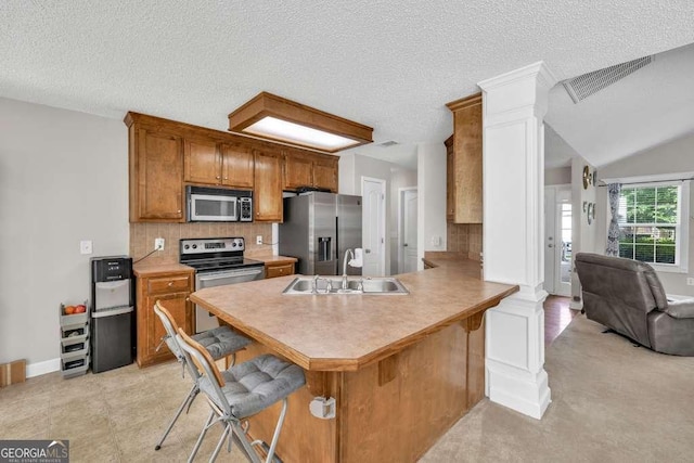 180 Laurel Oaks Ln, Jefferson, GA 30549 - kitchen with appliances with stainless steel finishes, decorative columns, a sink, a breakfast bar, and brown cabinetry