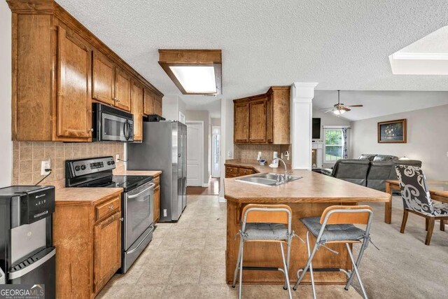 180 Laurel Oaks Ln, Jefferson, GA 30549 - kitchen with stainless steel electric stove, a sink, brown cabinetry, a textured ceiling, and tasteful backsplash