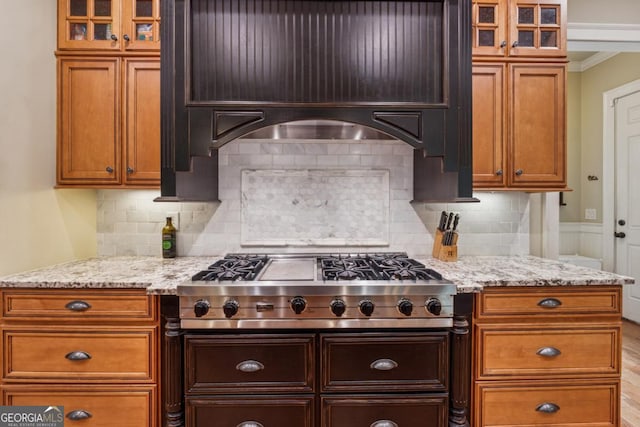 2551 Raintree Dr NE, Atlanta, GA 30345 - kitchen with crown molding, light stone counters, stainless steel gas stovetop, and glass insert cabinets