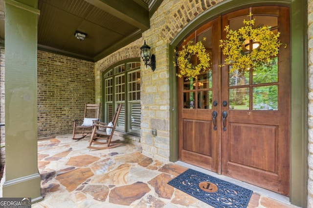 2551 Raintree Dr NE, Atlanta, GA 30345 - view of exterior entry featuring brick siding, french doors, stone siding, and covered porch
