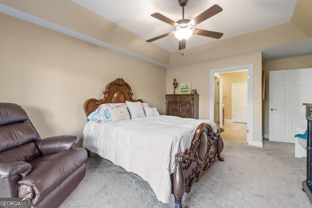 bedroom with ceiling fan, baseboards, a raised ceiling, and light colored carpet
