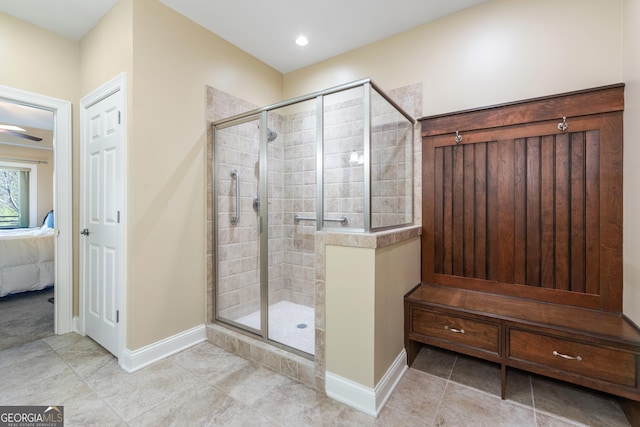 ensuite bathroom with connected bathroom, baseboards, tile patterned floors, and a stall shower