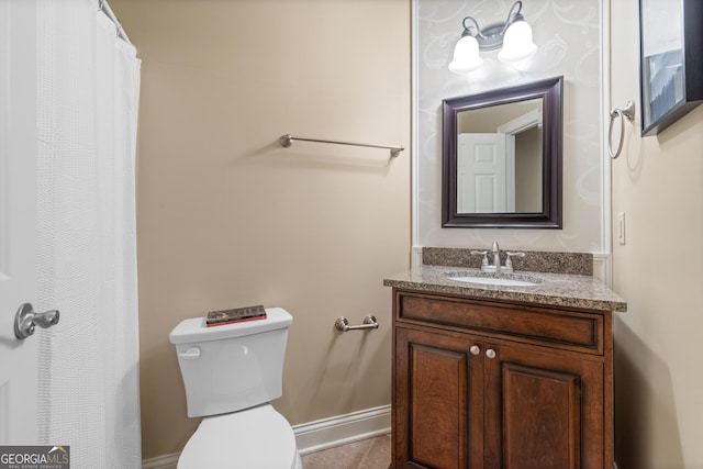 bathroom featuring toilet, vanity, and baseboards
