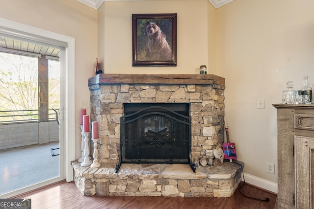 interior details featuring baseboards, wood finished floors, a fireplace, and crown molding