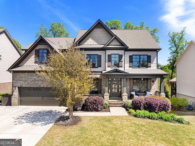 craftsman house with roof with shingles, concrete driveway, a garage, brick siding, and a front yard