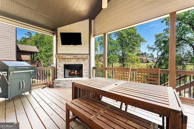 deck featuring outdoor dining area and an outdoor brick fireplace