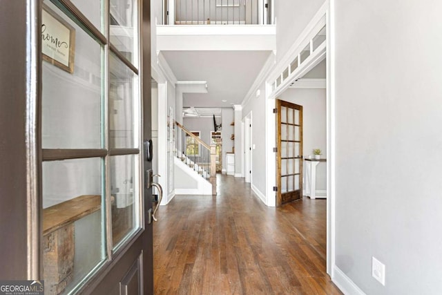 foyer featuring wood finished floors, stairs, french doors, baseboards, and ornamental molding