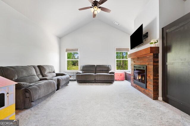 carpeted living area featuring a glass covered fireplace, vaulted ceiling, a wealth of natural light, and ceiling fan