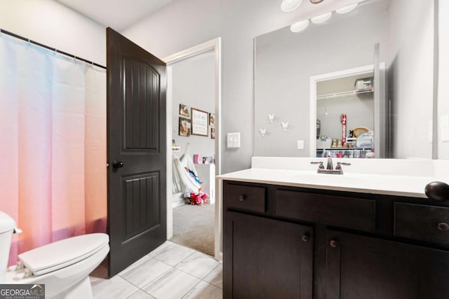 bathroom with marble finish floor, toilet, and vanity