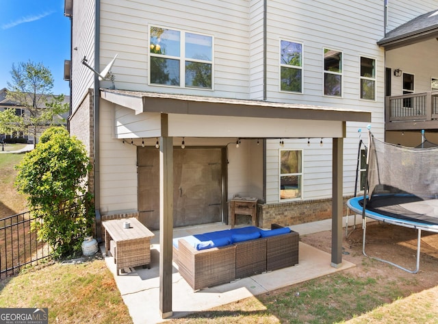 rear view of property featuring fence, a patio, outdoor lounge area, and a trampoline