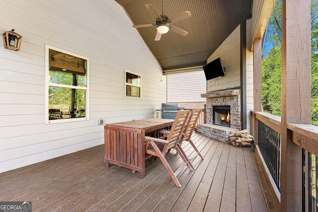 wooden terrace featuring ceiling fan, outdoor dining area, and an outdoor brick fireplace