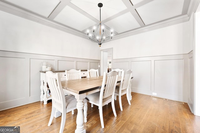 dining room with a chandelier, a decorative wall, and coffered ceiling