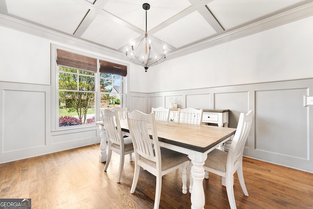 dining area with coffered ceiling, a decorative wall, crown molding, light wood-style flooring, and a notable chandelier