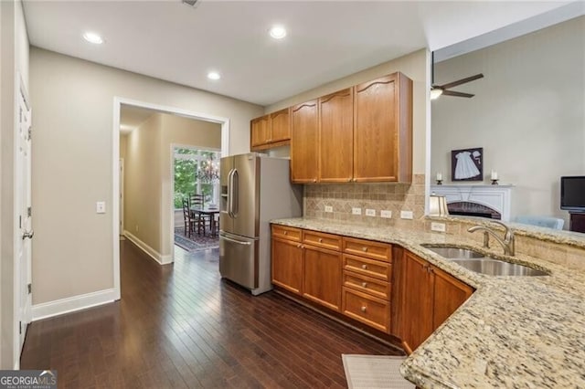 kitchen featuring stainless steel fridge with ice dispenser, a sink, light stone countertops, backsplash, and ceiling fan