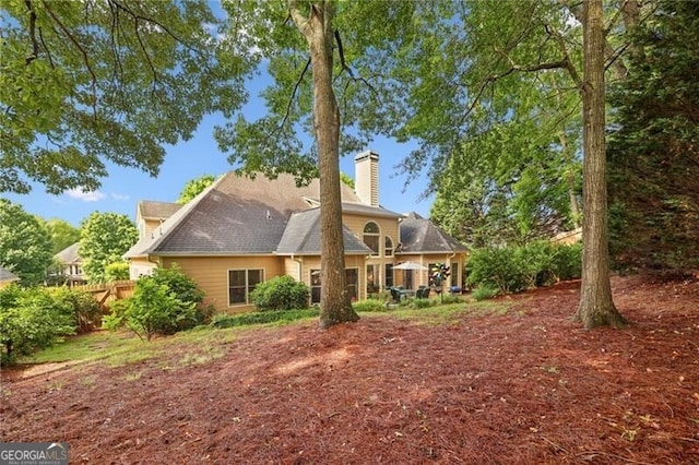 rear view of property with a chimney and fence
