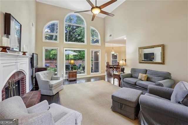 living area with healthy amount of natural light, a ceiling fan, high vaulted ceiling, a fireplace, and wood finished floors