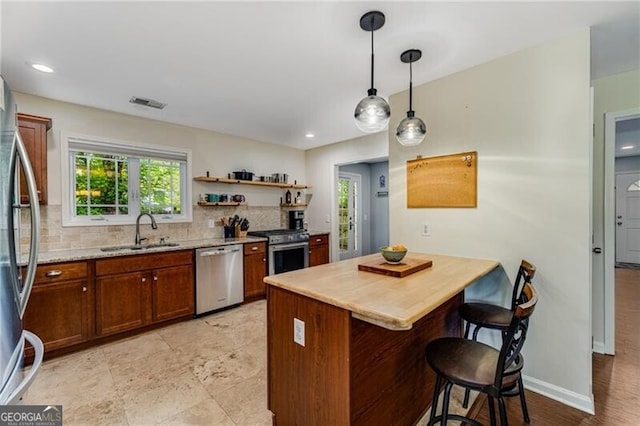 72 Griggs St SW, Marietta, GA 30064 - kitchen with appliances with stainless steel finishes, tasteful backsplash, a kitchen breakfast bar, decorative light fixtures, and brown cabinets