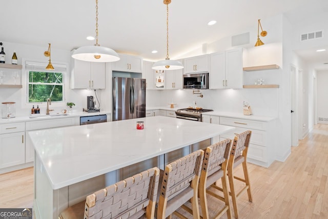 369 Arnold Mill Rd, Woodstock, GA 30188 - kitchen featuring appliances with stainless steel finishes, a center island, open shelves, a sink, and light wood finished floors