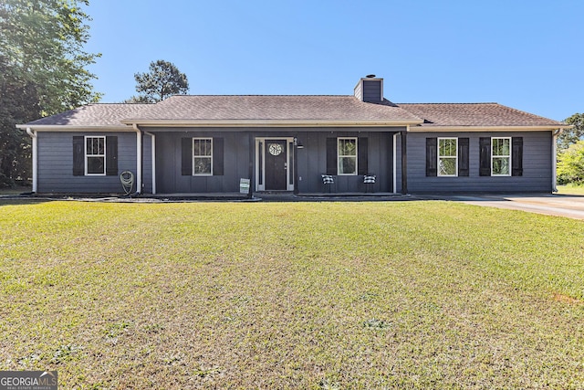 ranch-style home featuring a chimney, a front lawn, board and batten siding, covered porch, and roof with shingles
