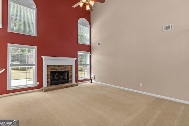 unfurnished living room featuring a towering ceiling, visible vents, and carpet flooring