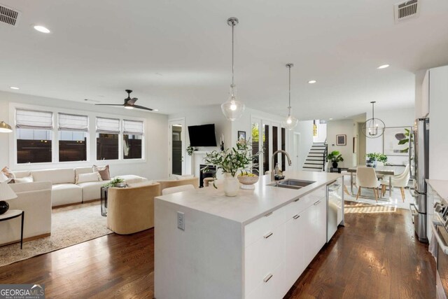 kitchen with stainless steel appliances, visible vents, white cabinetry, a sink, and dark wood-style flooring