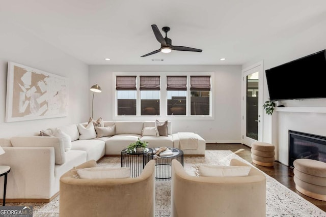 living area with a ceiling fan, a glass covered fireplace, visible vents, and recessed lighting
