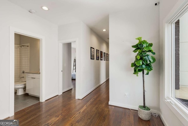 hallway featuring baseboards, wood finished floors, and recessed lighting