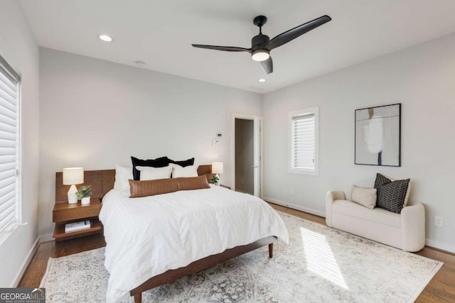 bedroom with wood finished floors, baseboards, and multiple windows