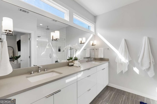 bathroom featuring visible vents, a sink, a shower stall, and double vanity