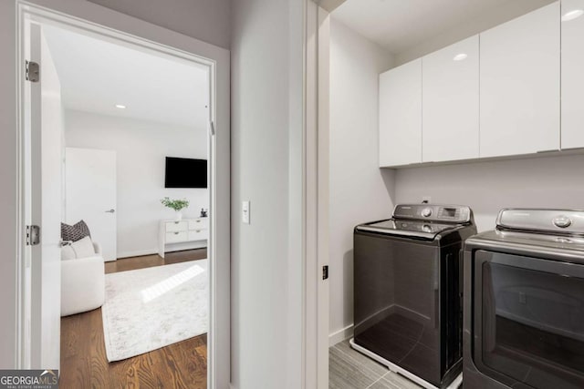 laundry room featuring baseboards, independent washer and dryer, dark wood-type flooring, and cabinet space