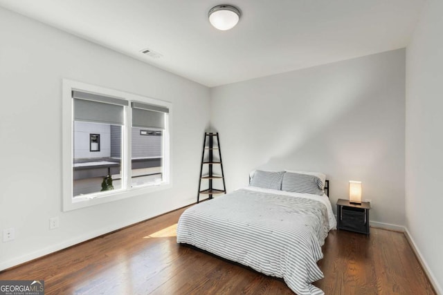bedroom featuring wood finished floors, visible vents, and baseboards