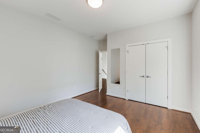 bedroom featuring visible vents, baseboards, wood finished floors, and a closet