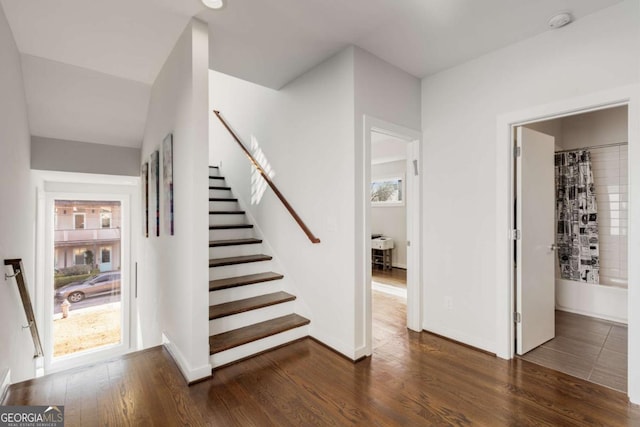 staircase featuring wood finished floors, a healthy amount of sunlight, and baseboards